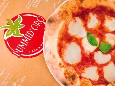 Eine köstliche Margherita-Pizza mit Tomatensoße, Mozzarella und Basilikum liegt appetitlich neben einer PUMMID'ORO Pizzabox auf der Costa Diadema.
