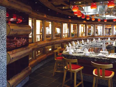 Das Teppanyaki-Restaurant an Bord der Costa Diadema: Geschwungener Tresen mit gedeckten Plätzen, roten Hockern. Holzwände und rote Hängelampen schaffen warme Stimmung.