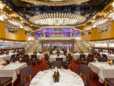 Das elegante Restaurant an Bord der Costa Diadema. Zahlreiche festlich gedeckte Tische. Goldene Decken, beleuchtete Treppen und opulente Lichtinstallation prägen den luxuriösen Raum.