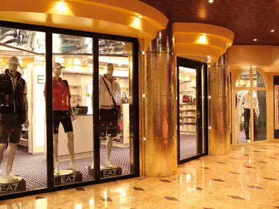 Blick auf die Schaufenster der Armani-Boutique an Bord der Costa Fascinosa mit Sportbekleidung und goldenen Säulenelementen.