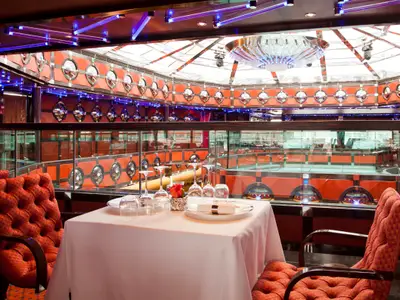 Ein edel gedeckter Tisch mit roten Polstersesseln im Club-Restaurant an Bord der Costa Fascinosa.