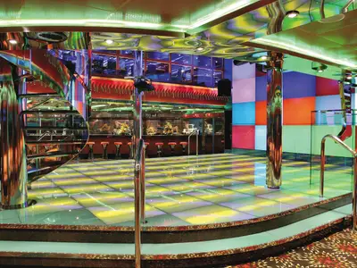 Blick in die helle und farbenfrohe Disco Vulcania 1927 der Costa Fortuna mit beleuchtetem Dancefloor, Bar und Wendeltreppe.