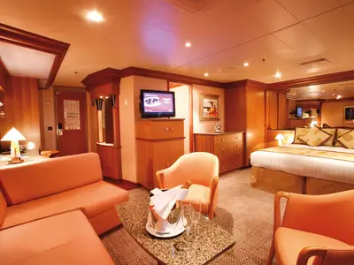 Innenansicht der geräumigen Grand Suite an Bord der Costa Pacifica mit Doppelbett, Sofaecke und Sektkühler.