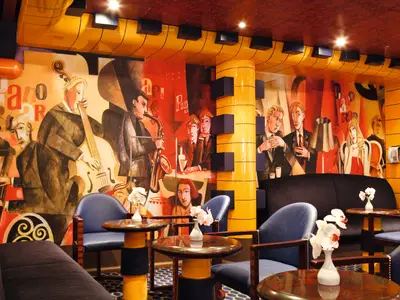 Die Rick's Piano Bar an Bord der Costa Pacifica bietet blaue Sessel, kleine Tische und ein großes Wandgemälde mit Jazzmusikern.