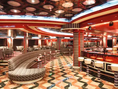 Die auffällige Around the Clock Lounge an Bord der Costa Pacifica. Rote Wände, Decken, Bar mit weißen Hockern, gemusterte Sofas, geometrischer Boden. Heller Innenraum ohne Personen.