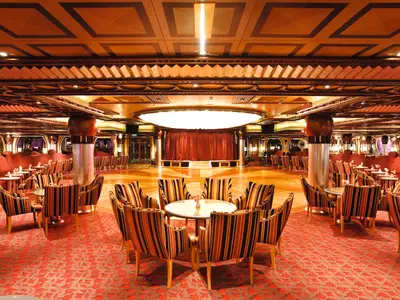 Blick in die elegante, mit gestreiften Sesseln und Holzelementen gestaltete Grand Bar Rhapsody an Bord der Costa Pacifica.