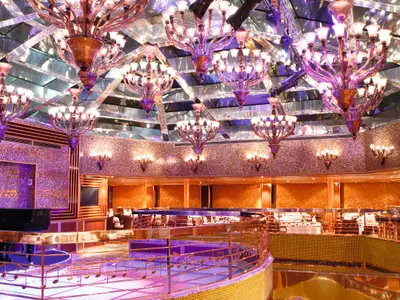 Blick in das prachtvolle Club Blue Moon Restaurant an Bord der Costa Pacifica mit opulenten, violett schimmernden Kronleuchtern.