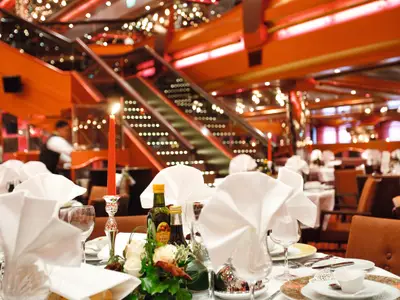 Festlich gedeckter Tisch mit roter Kerze, feinen Gläsern und Servietten im Restaurant an Bord der Costa Pacifica.