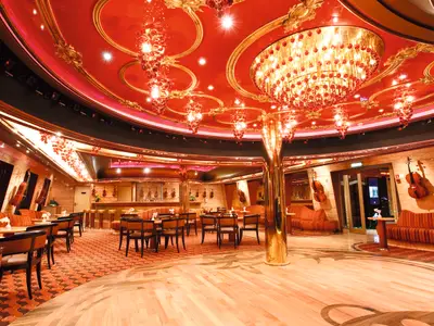 Elegante Wien Wien Bar-Lounge an Bord der Costa Pacifica. Rote, goldverzierte Decke, prächtige Kronleuchter, Sitzgruppen und Bar. Streichinstrumente an den Wänden.