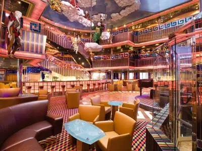 Farbenprächtiges Pantheon-Atrium an Bord der Costa Serena mit bequemen Clubsesseln, einer Bar, Klavier und hängenden Kunstfiguren.