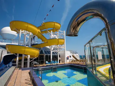 Gelbe Wasserrutsche und kleiner Pool mit Ankermotiv auf dem Außendeck an Bord der Costa Serena unter blauem Himmel.