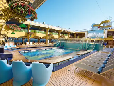 Der einladende Poolbereich an Bord der Costa Serena mit einem Schwimmbecken, Liegestühlen, blauen Sesseln und einer Wasserrutsche.