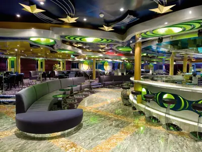 Einblick in die Luna Lounge an Bord der Costa Serena mit runder Bar, Barhockern und lila Polstermöbeln.