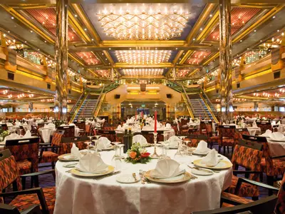 Das prunkvolle, festlich geschmückte Restaurant Vesta an Bord der Costa Serena mit goldenen Säulen und Freitreppen.