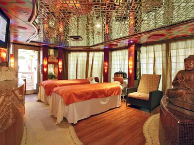 Samsara Spa Behandlungsraum an Bord der Costa Serena mit zwei Massageliegen, einer Buddha-Statue und warmer Beleuchtung.
