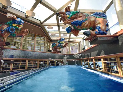 Ein blubbernder Thalasso-Pool im Samsara Spa an Bord der Costa Serena mit bunten, asiatischen Skulpturen unter einem Glasdach.