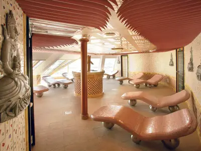 Blick in das Tepidarium im Samsara Spa an Bord der Costa Serena mit geschwungenen rosa Mosaik-Liegen und Wandreliefs.