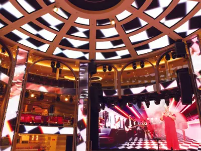 Sängerin und Musiker performen auf einer Bühne mit LED-Wänden im Atrium an Bord der Costa Smeralda.