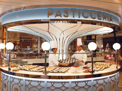 Zwei Konditoren in weißer Arbeitskleidung präsentieren eine Auswahl an Desserts an Bord der Costa Smeralda.