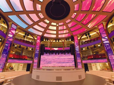 Das beeindruckende, mehrstöckige Atrium Colosseo an Bord der Costa Smeralda mit einer runden Bühne und riesigen LED-Bildschirmen.