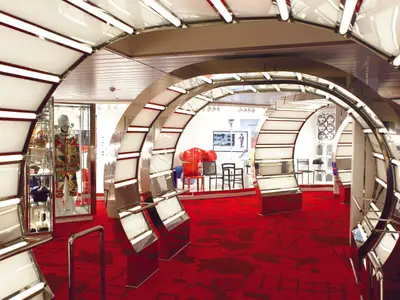 Einblick in das moderne Designmuseum CoDe an Bord der Costa Smeralda mit futuristischen Lichtbögen und rotem Teppich.