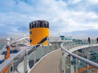 Auf dem Außendeck der Costa Smeralda führt ein geschwungener Glas-Skywalk am markanten gelben Schornstein vorbei.