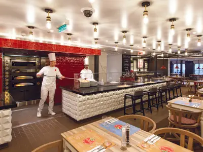 Zwei Pizzabäcker bereiten an Bord der Costa Smeralda frische Pizzen vor dem traditionellen Ofen zu.