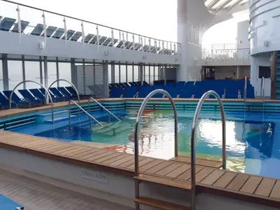 Ein leerer Swimmingpool auf dem offenen Deck 17 der Costa Smeralda mit blauen Liegestühlen im Hintergrund.