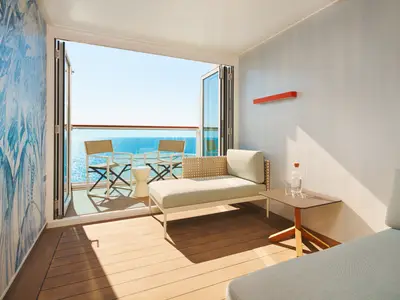 Blick aus einer gemütlichen Balkonkabine an Bord der Costa Toscana auf das blaue Meer bei strahlendem Sonnenschein.