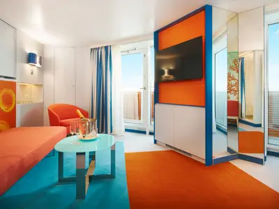 Eine farbenfroh gestaltete Suite an Bord der Costa Toscana mit orangefarbenem Sofa, blauem Tisch und Balkonzugang.