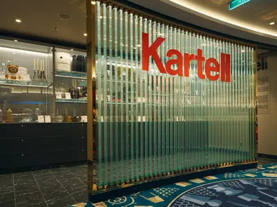Blick auf den eleganten Kartell-Ausstellungsbereich an Bord der Costa Toscana mit gläserner Trennwand und beleuchteten Vitrinen.