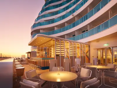 Terrazza Infinity Outdoor-Bar der Costa Toscana am Abend. Moderne Bar, Sitzgruppen und Schiffsbalkone unter Himmel.