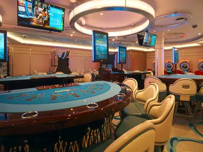 Blick auf Spieltische für Kartenspiele und Automaten im modernen Casino Granducato an Bord der Costa Toscana.
