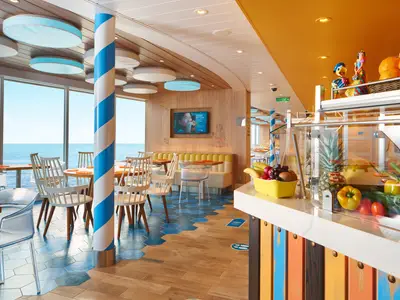 Modernes Restaurant Squoak an Bord der Costa Toscana mit Meerblick. Frisches Obst und Gemüse am Buffet. Helle, farbenfrohe Einrichtung mit Holz und blau-weißem Pfeiler.