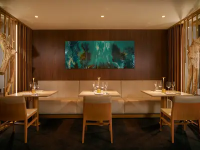 Elegante Sitzbänke, eingedeckte Tische und moderne Holzkunst im Restaurant Archipelago an Bord der Costa Toscana.