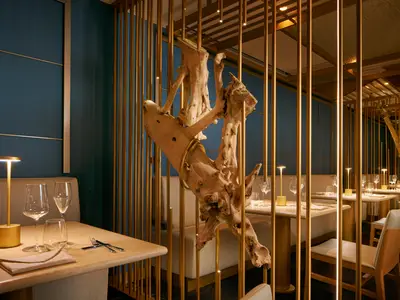 Gedeckte Tische und dekorative Treibholz-Elemente im Restaurant Archipelago an Bord der Costa Toscana.