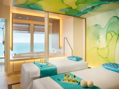 Zwei Massageliegen in einem luxuriösen Spa-Raum der Costa Toscana mit Blick auf das Meer durch große Fenster. Ein privater Whirlpool ist ebenfalls sichtbar.