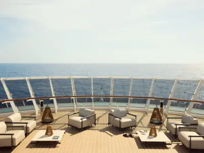 Blick vom Sonnendeck der Explora I auf das offene Meer mit modernen Lounge-Sesseln und Holzdekor.