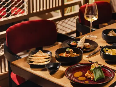 Aufwendig angerichtete asiatische Speisen, Curry und Fladenbrot auf einem Holztisch im Restaurant an Bord der Explora I.
