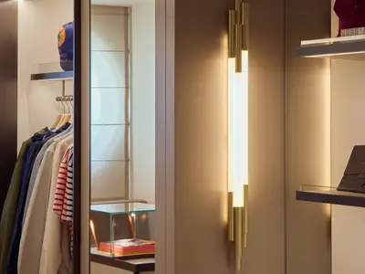 Detailansicht eines Luxus-Shops an Bord der Explora I mit Kleiderständer, eleganter Wandleuchte und Regalen.