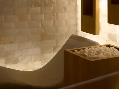 Holzbehälter gefüllt mit weißen Salzsteinen vor einer beleuchteten Salzwand im Spa an Bord der Explora I.