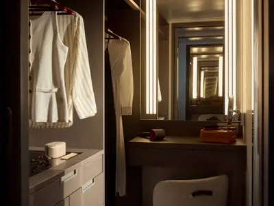 Beleuchteter Schminktisch mit Haartrockner und Ankleidebereich in einer Suite an Bord der Explora I.