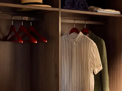 Nahaufnahme eines begehbaren Kleiderschranks aus Holz mit Kleidung in einer Suite an Bord der Explora I.