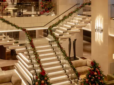 Beleuchtete, elegante Freitreppe mit Weihnachtsgirlanden und Glaselementen im Atrium der Explora II.