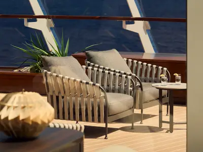Zwei gemütliche Sessel und ein Beistelltisch mit Erfrischungsgetränken auf dem Deck an Bord der Explora II.