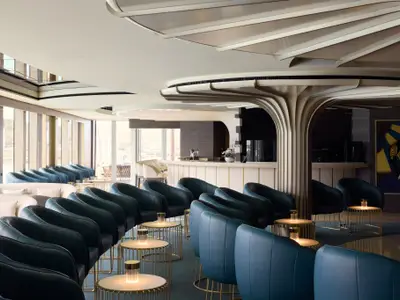 Stilvolle Astern Lounge an Bord der Explora II mit teal-farbenen Ledersesseln, goldenen Tischen und Bar.