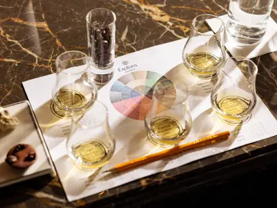 Gläser mit Whisky, Schokolade und ein Verkostungsbogen auf einem Marmortisch an Bord der Explora II.