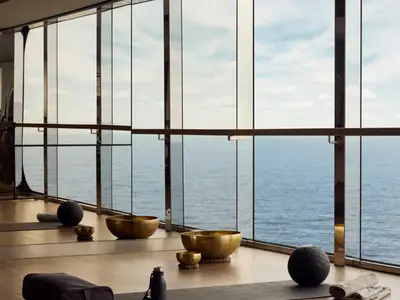 Klangschalen und Gymnastikbälle in einem hellen Yogaraum mit Panoramaglasfront zum Meer an Bord der Explora II.