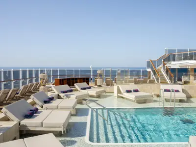Sonnendeck mit Pool und komfortablen Liegen bei sonnigem Wetter an Bord der Explora II.