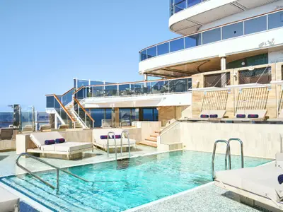 Ein türkisfarbener Pool mit Edelstahlleitern und bequemen Sonnenliegen auf dem Sonnendeck an Bord der Explora II.